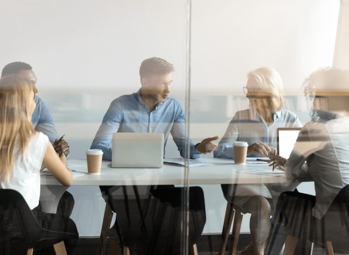 A diverse group of professionals discussing ideas and collaborating at a table in a meeting room.
