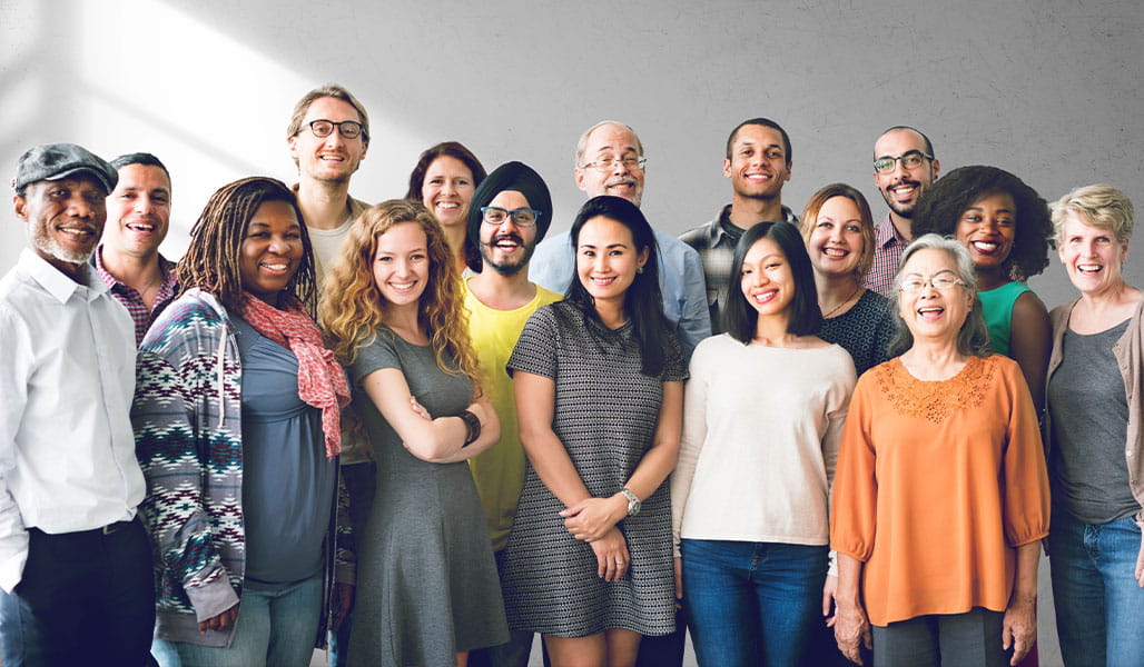 A diverse group of people standing together, varying from different ages and ethnicities.
