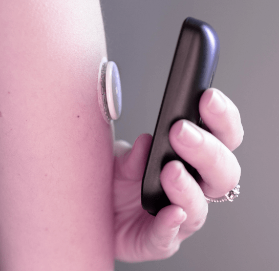 A person holding a device to check the blood sugar level.