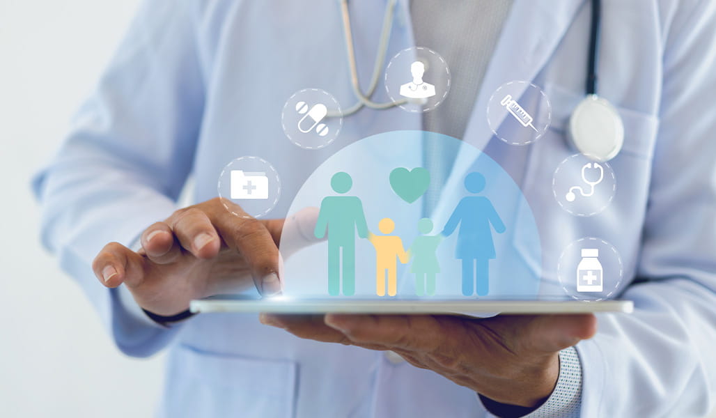 A healthcare professional holds a tablet displaying family health icons and symbols.