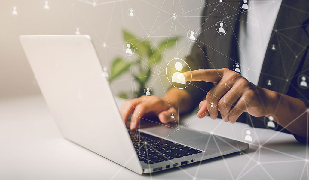 A person interacts with a laptop, searching a network of people.