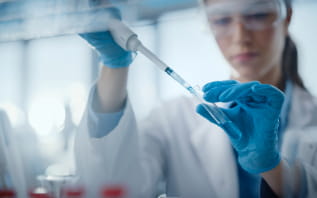 A female scientist in a lab coat holds a tube, conducting experiments in a laboratory setting.