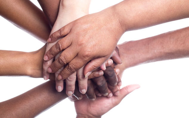 Hands of different ethnicities stacked on top of each other.