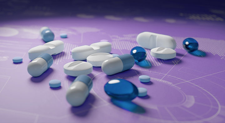 Assorted pills and capsules of varying sizes and colors scattered on a surface.