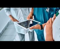 Healthcare professionals collaborating around a tablet device.