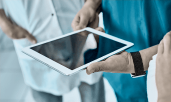 Healthcare professionals collaborating around a tablet device.