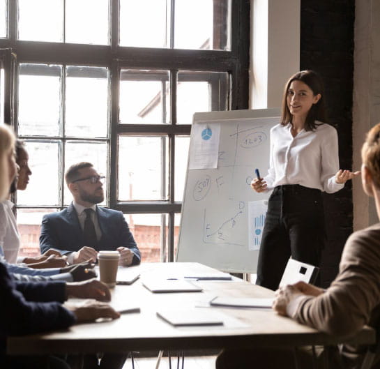 Person in front of a whiteboard talking to a group of people.